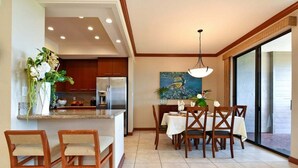 Une cuisine moderne avec un îlot central, des chaises en bois, une table à manger et une grande fenêtre.