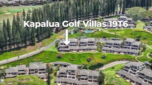 Vue aérienne du complexe Kapalua Golf Villas 19T6, qui présente un ensemble de villas modernes avec un terrain de golf et une vue sur l’océan.
