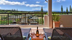 Un balcon avec une table dressée pour deux personnes, une bouteille de vin et deux verres.