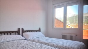 A bedroom with two beds, a window, and a radiator.