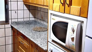 A kitchen with wooden cabinets, a granite countertop, a microwave, and an oven.