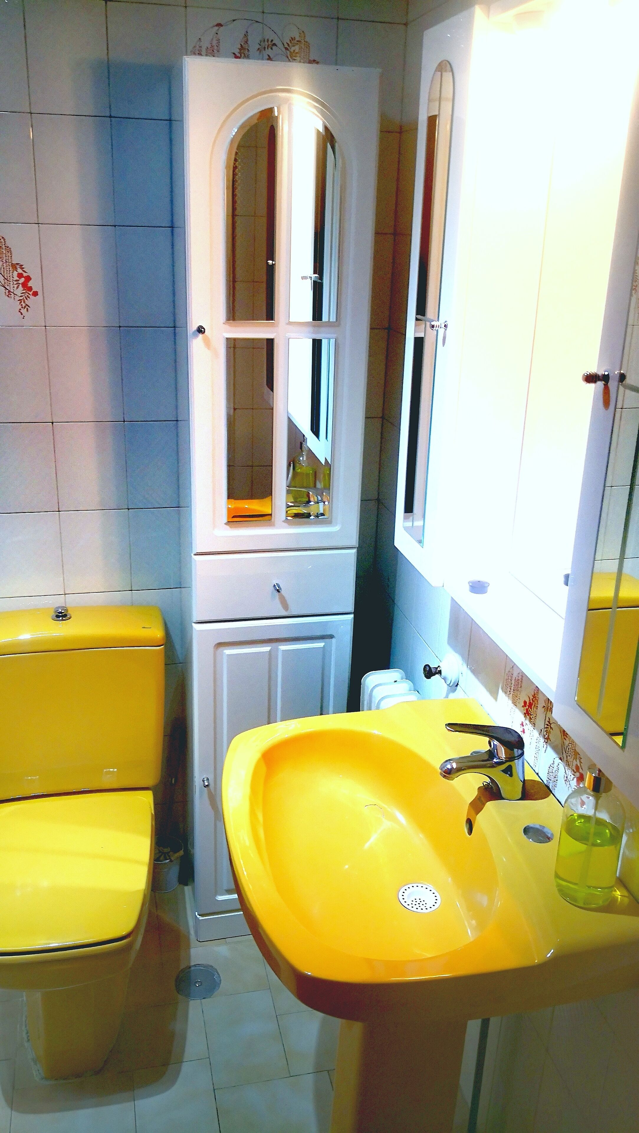 Un bagno con un lavandino giallo, un armadietto bianco con uno specchio e un water giallo.