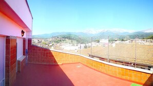A balcony with a red floor and a view of a stadium and mountains.