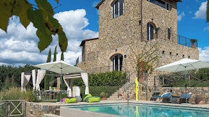 Un bâtiment en pierre doté d’une piscine, d’un espace extérieur aménagé et d’une pergola.