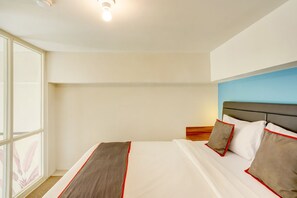 A hotel room with a large window, a bed with white bedding and red trim, and a blue accent wall. - Super OYO Collection O 30 Amega Crown Sub (Surabaya)