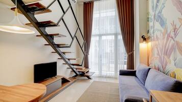 Un intérieur moderne comprenant un escalier, un téléviseur à écran plat, un canapé et un coin repas.