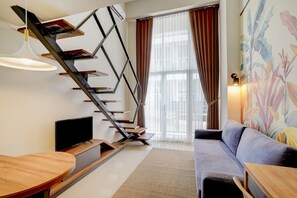 A modern interior with a staircase, a flat-screen TV, a sofa, and a dining area. - Super OYO Collection O 30 Amega Crown Sub (Surabaya)