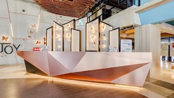 Un comptoir d’accueil moderne au design géométrique, agrémenté d’un logo et de décorations murales en forme de papillons.