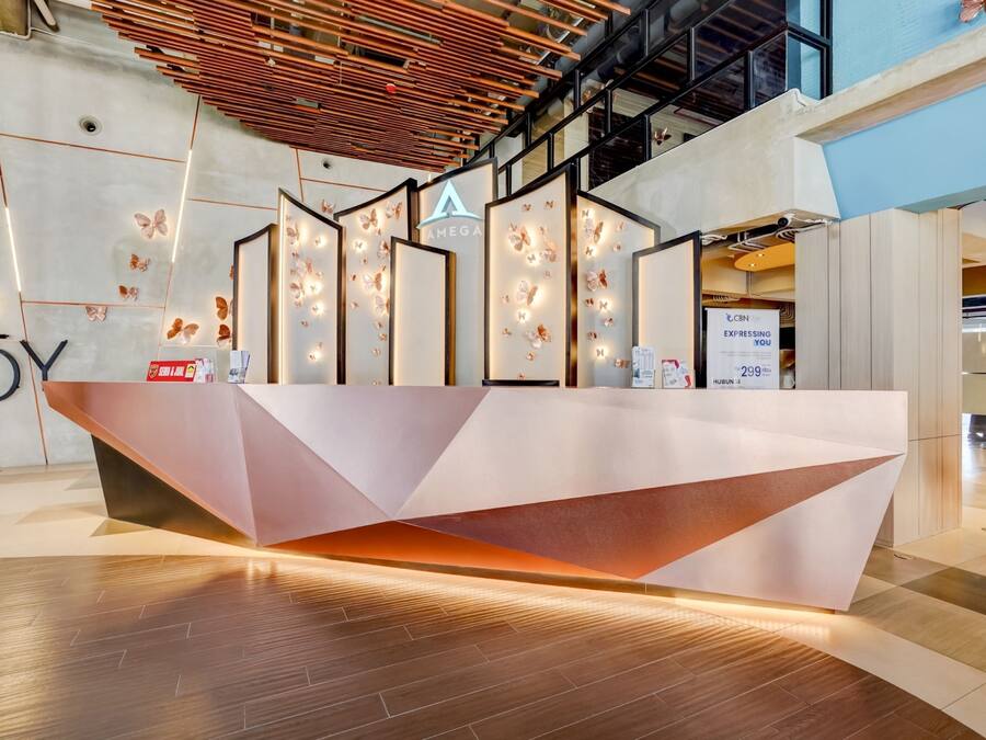 Un mostrador de recepción moderno con diseño geométrico, un logotipo y decoración de pared con mariposas.