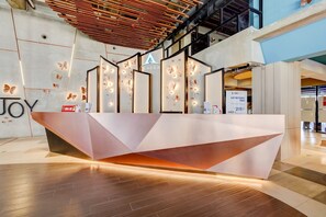 A modern reception desk with geometric design, a logo, and butterfly wall decor. - Super OYO Collection O 30 Amega Crown Sub (Surabaya)