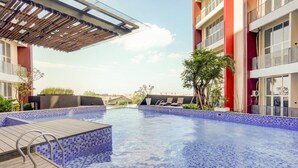 Piscina com bordas azulejadas, deck de madeira e grades de metal.