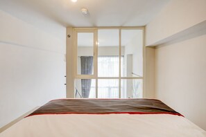 A bedroom with a bed, a sliding door leading to a balcony, and a window with curtains. - Super OYO Collection O 30 Amega Crown Sub (Surabaya)
