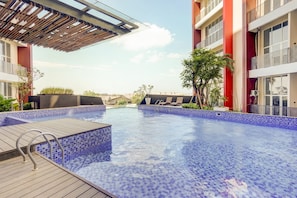 A swimming pool with tiled edges, wooden deck, and metal railings. - Super OYO Collection O 30 Amega Crown Sub (Surabaya)