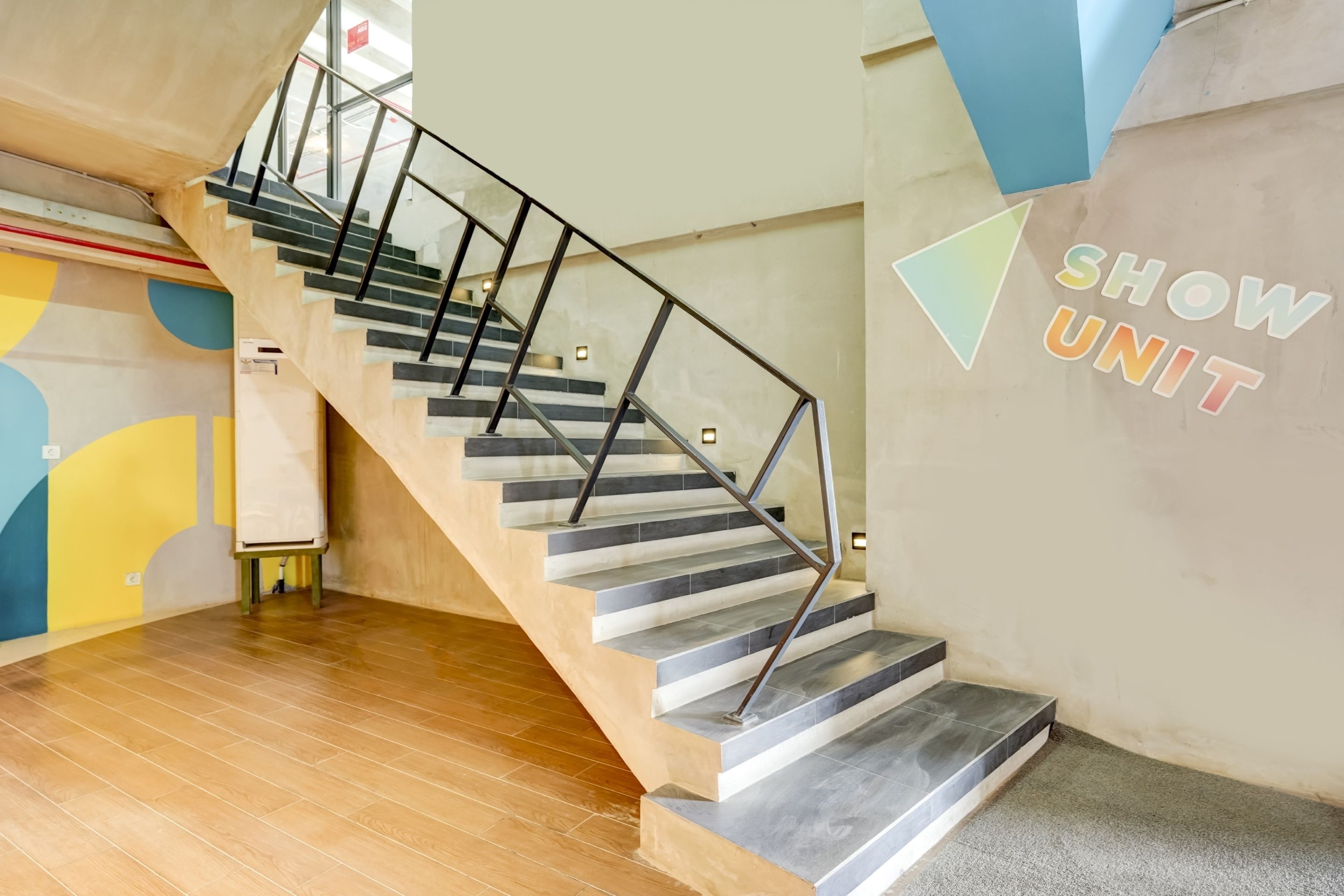 Un interior moderno con una escalera, suelo de madera y una pared que dice 'SHOW UNIT'.