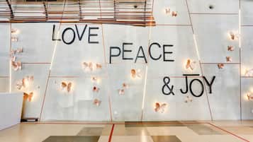 A wall with the words 'LOVE PEACE & JOY' and decorative butterfly lights.