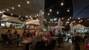 An outdoor dining area with tables and chairs, string lights overhead, and umbrellas providing shade. - Big Family House 5 Minutes from Lake Michigan/Blue Chip Casino/Brewery/Wineries! (Michigan City)