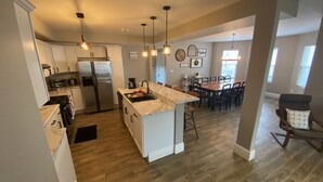 A spacious kitchen with a central island, a dining area with a large table, and a cozy seating area with a chair. - Big Family House 5 Minutes from Lake Michigan/Blue Chip Casino/Brewery/Wineries! (Michigan City)