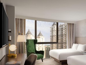 A hotel room with a bed, a desk with a lamp, a chair, and a large window offering a city view. - The Starling Atlanta Midtown, Curio Collection by Hilton (Atlanta)