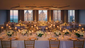 A banquet hall with multiple round tables set for dining, each with white tablecloths, candles, and floral centerpieces. - The Starling Atlanta Midtown, Curio Collection by Hilton (Atlanta)