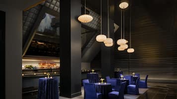 A modern bar area with tiered seating and hanging pendant lights.