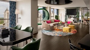A modern hotel room with a large window, a sofa, a dining area, and a TV. - The Starling Atlanta Midtown, Curio Collection by Hilton (Atlanta)