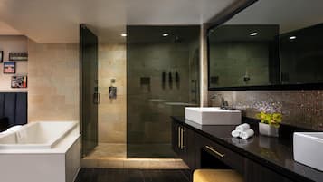 Een moderne badkamer met een douchecabine van glas, een wit bad en donkere kastjes, plus een grote spiegel.