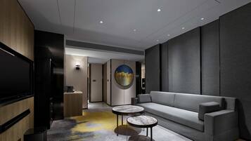 A modern living room with a grey sofa, two marble-topped coffee tables, a flat-screen TV, and a cityscape painting on the wall.