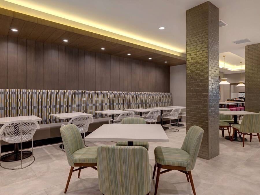 Un restaurante moderno con mesas y sillas altas, un pared con diseño y una columna de ladrillo.