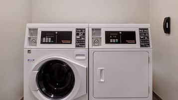 Two front-loading washing machines with digital control panels, a wall-mounted telephone, and a tiled floor.