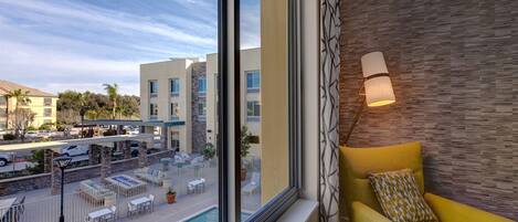 A hotel room with a large window, a yellow armchair, a pool view, and a modern wall design.