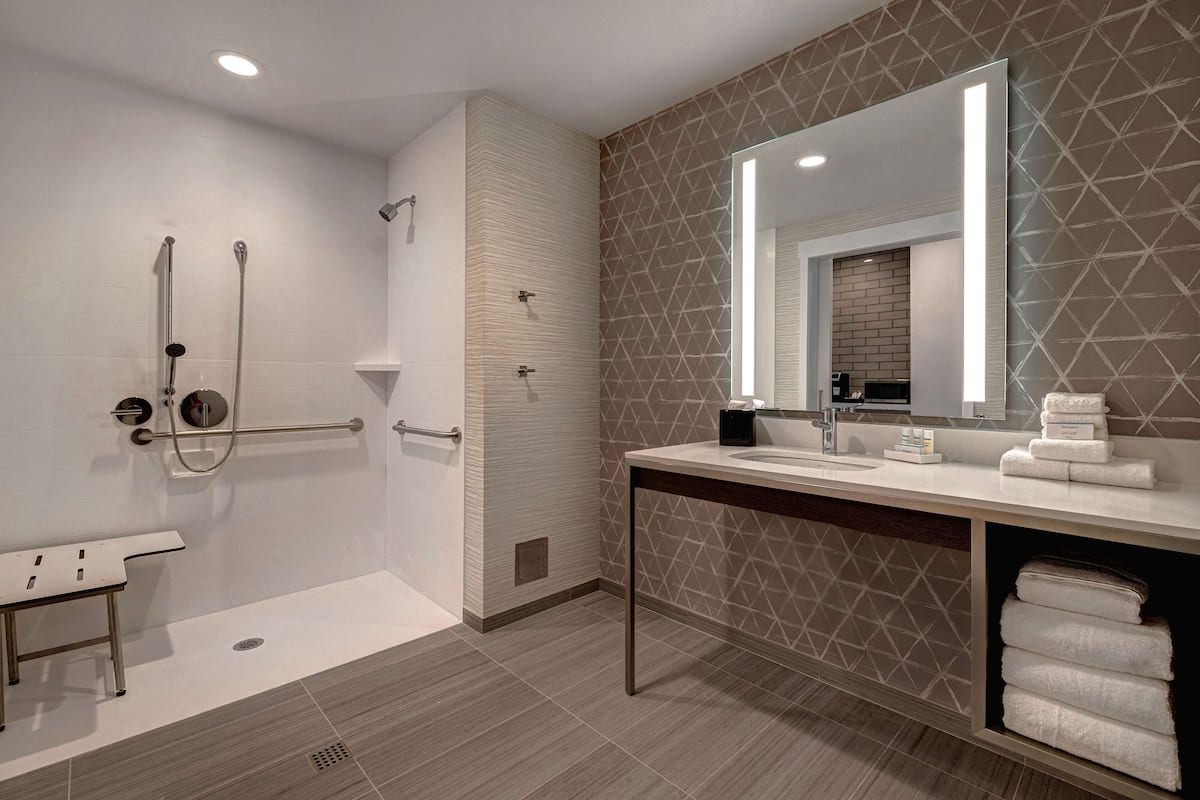 A modern bathroom with a walk-in shower, a vanity with a mirror, and a towel rack.