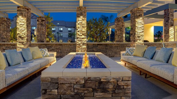 An outdoor seating area with stone pillars, a fire feature, and a covered pergola. - Hilton Garden Inn Temecula, CA (Temecula)