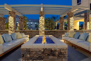 An outdoor seating area with stone pillars, a fire feature, and a covered pergola.