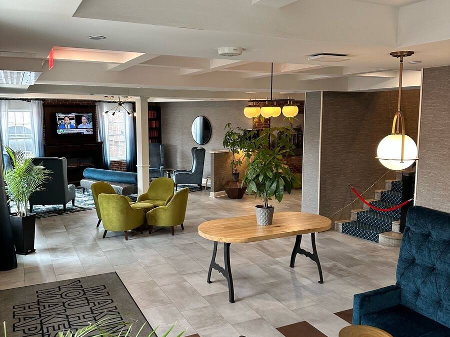 A modern hotel lobby with a seating area, a television, and a large plant.