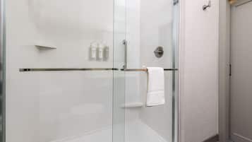 Une salle de bain moderne avec une douche à l’italienne en verre, des carreaux blancs et un porte-serviettes.