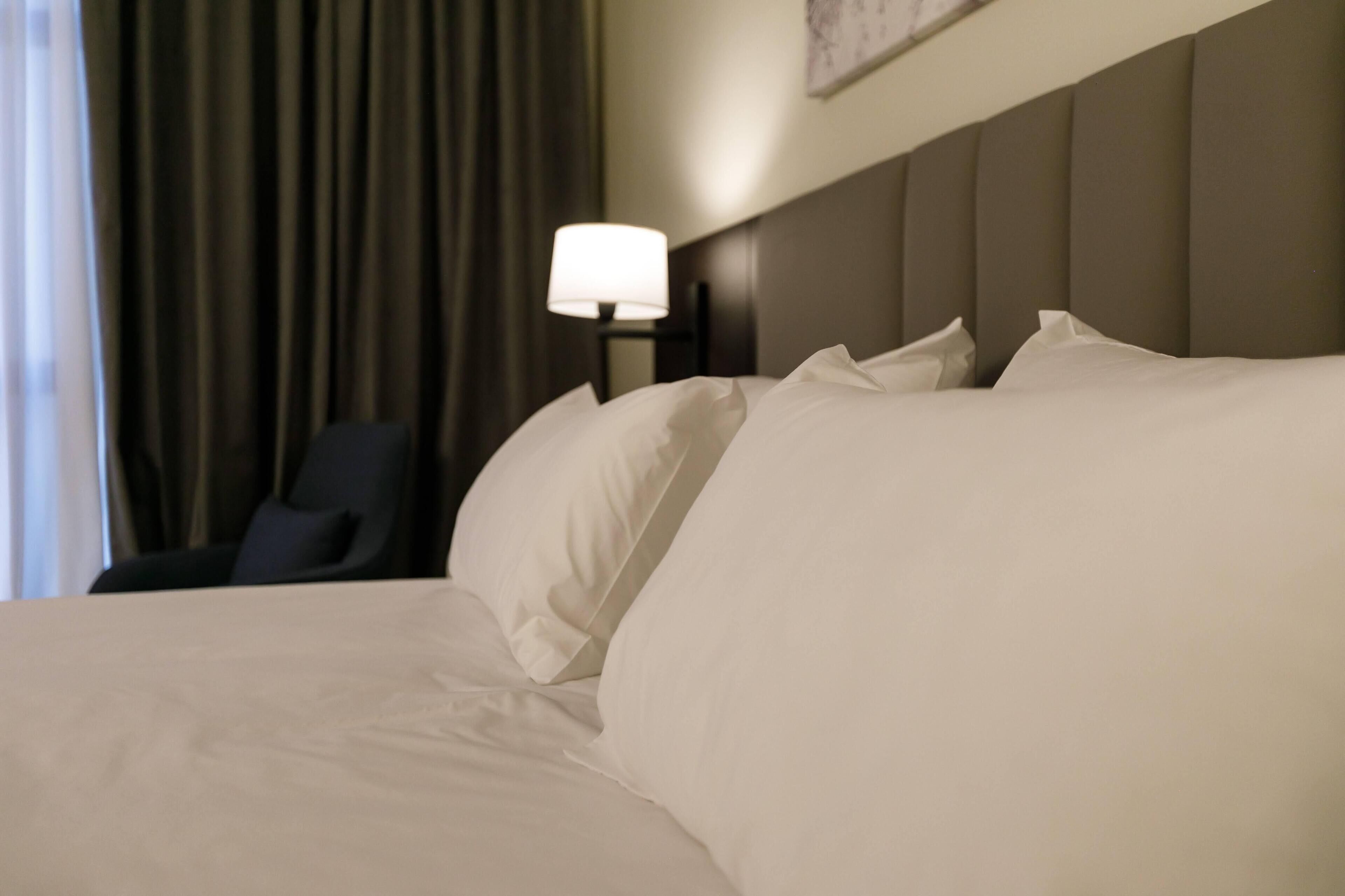 Une chambre d’hôtel avec un grand lit, une table de chevet avec une lampe et une chaise.