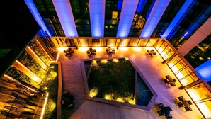 An aerial view of a modern building with a central courtyard, multiple seating areas, and a staircase leading to an upper level.