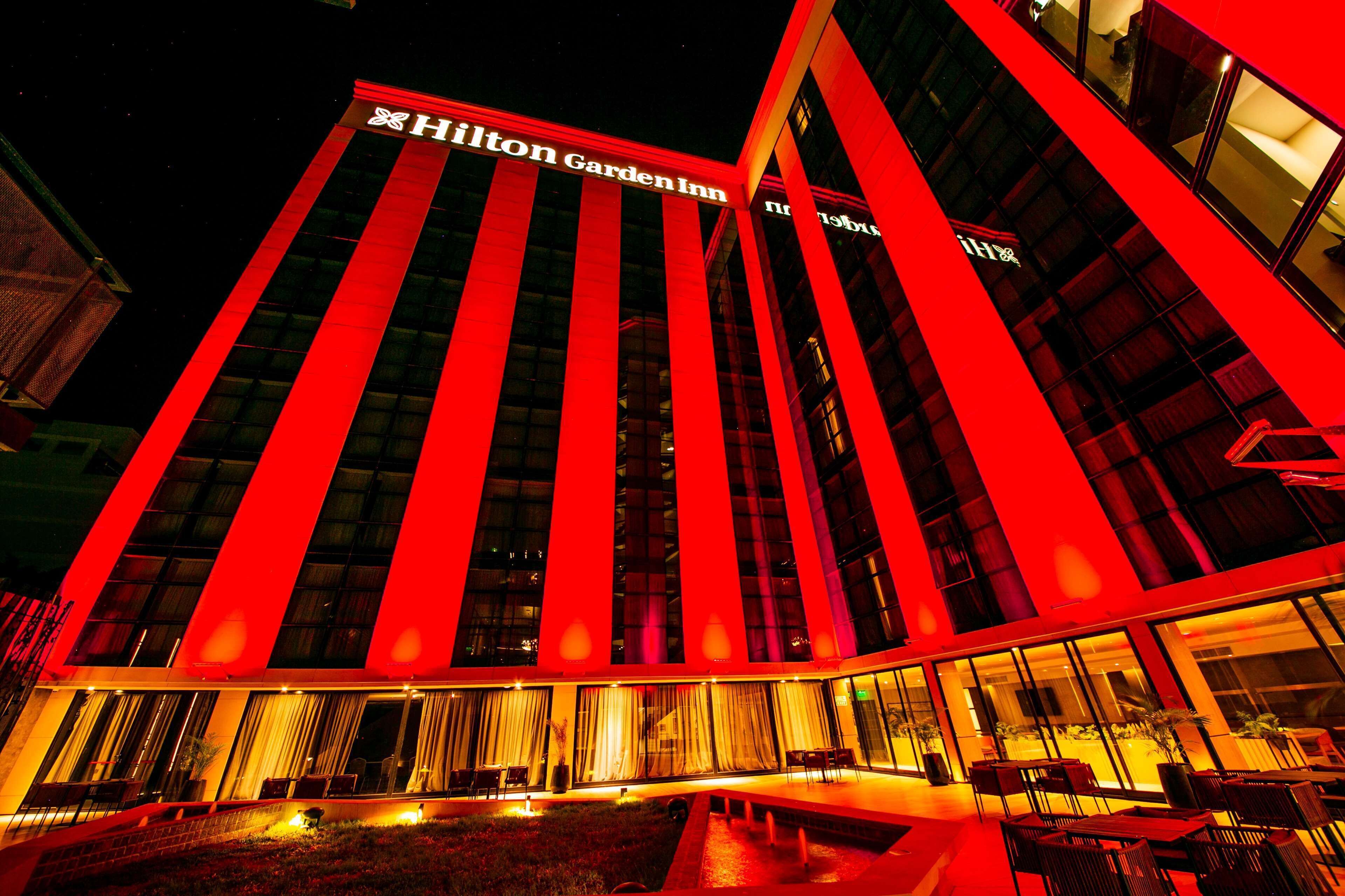 A Hilton Garden Inn hotel with a modern design, featuring large windows and a well-lit exterior.