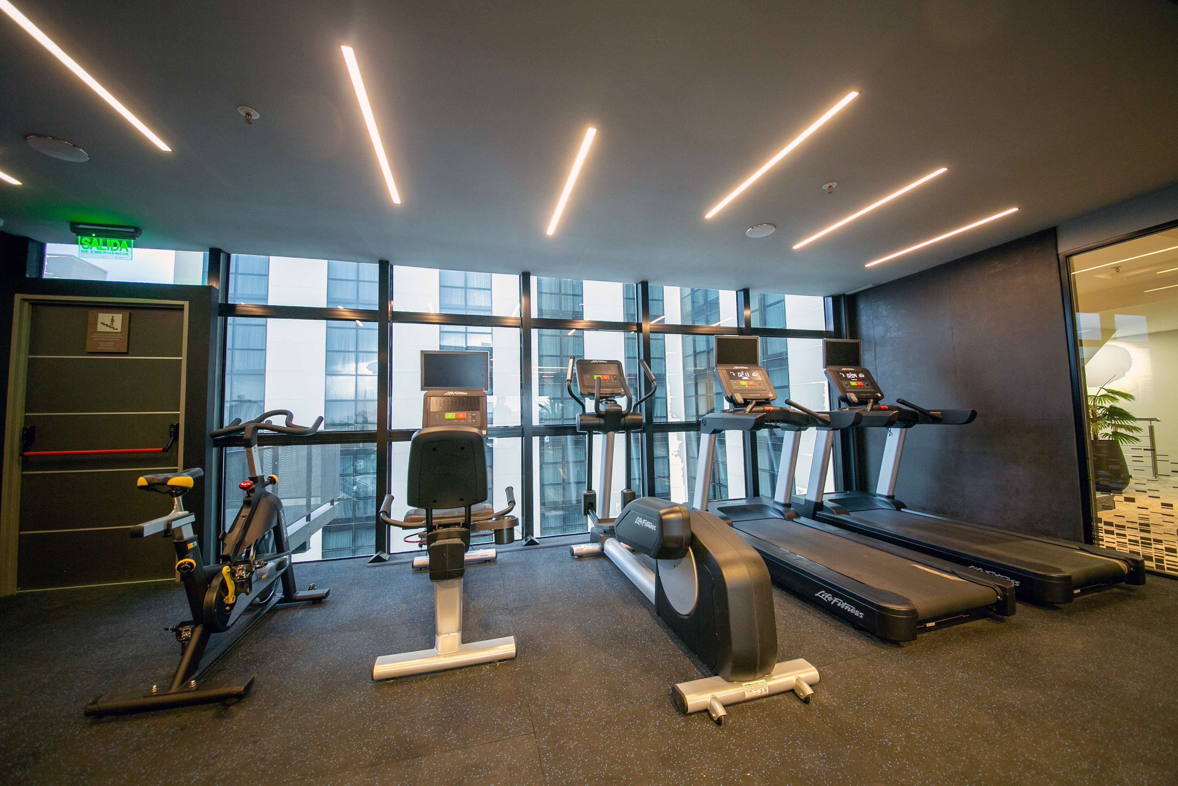 A modern gym with treadmills, stationary bikes, and weight machines.