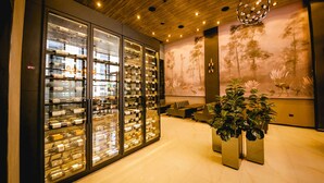 A modern interior with a wine display, seating area, and a large plant.