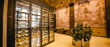 A modern interior with a wine display, seating area, and a large plant.