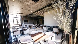 A modern indoor dining area with white furniture, a wooden table, and a large potted plant.