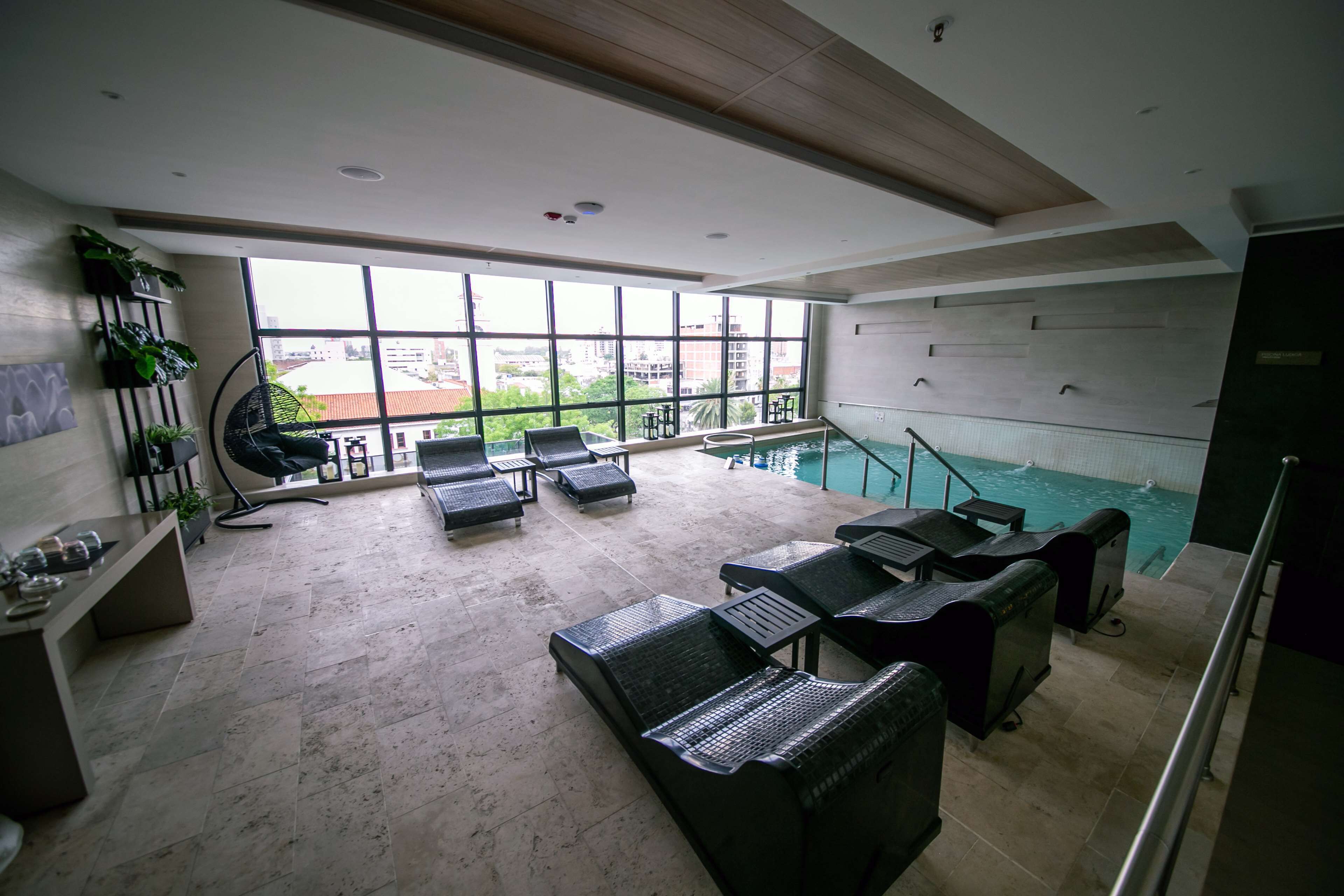 Area piscina interna moderna con poltrone relax e reception.