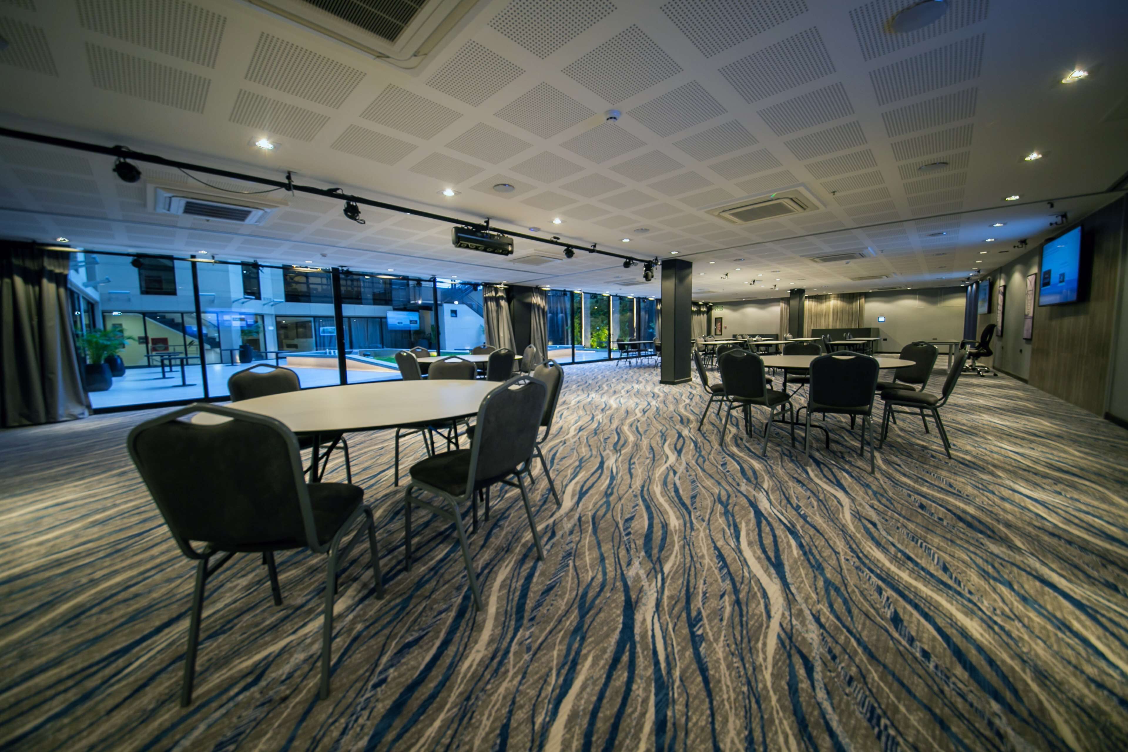 A conference room with a large table, multiple chairs, and a carpeted floor.