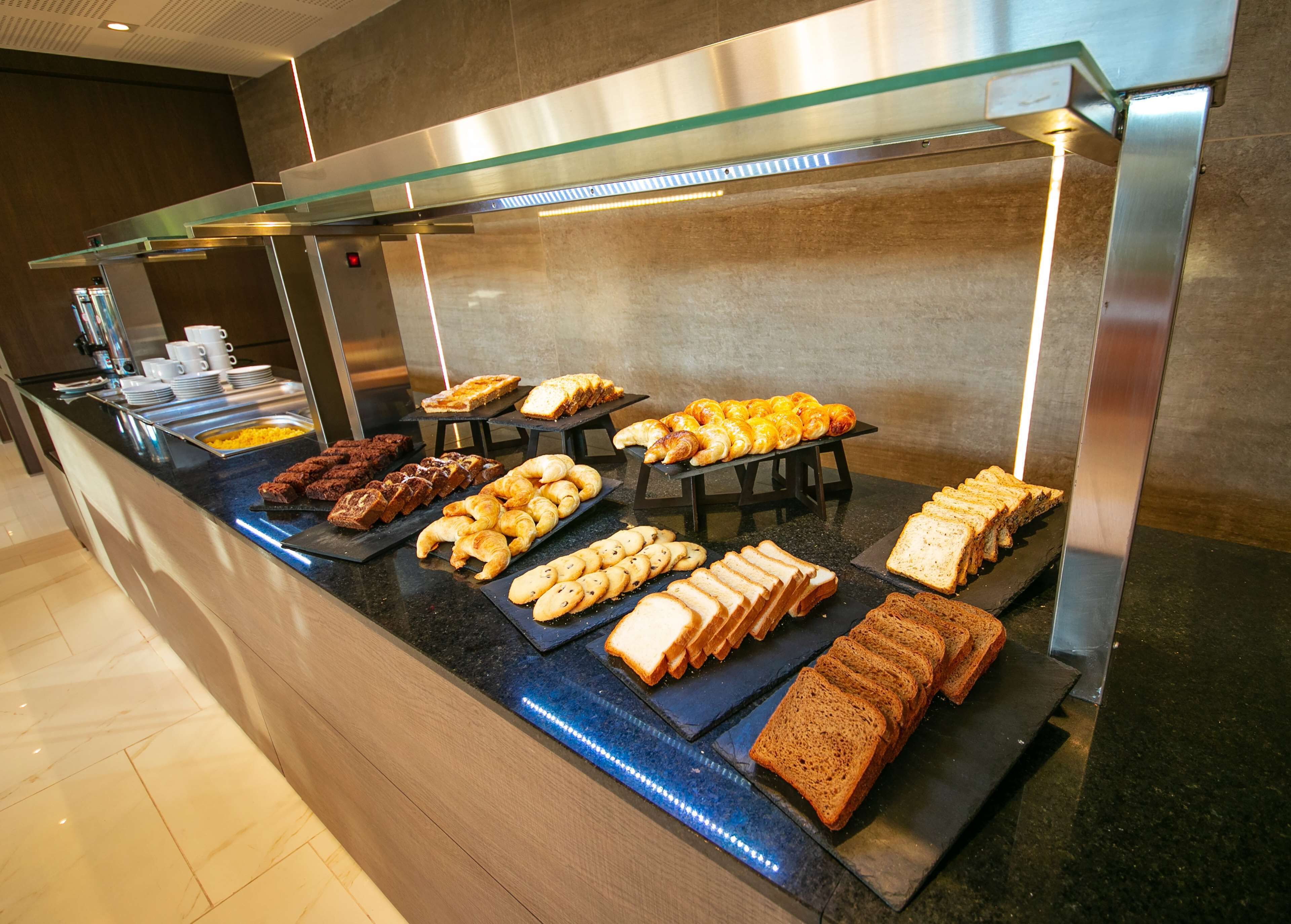 A buffet with various food items including bread, pastries, and desserts.