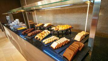 A buffet with various food items including bread, pastries, and desserts.