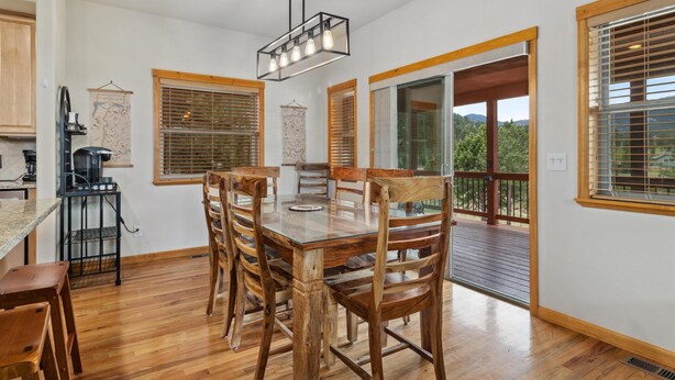 Una cocina moderna con armarios de madera, una mesa de comedor con sillas y una lámpara colgante.
