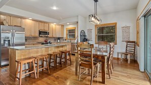 Una cocina moderna con armarios de madera, electrodomésticos de acero inoxidable y una isla central con taburetes de bar.