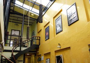 A multi-level interior with a spiral staircase, yellow walls, and various framed pictures. - Onde Pepe Hostel (Bogotá)
