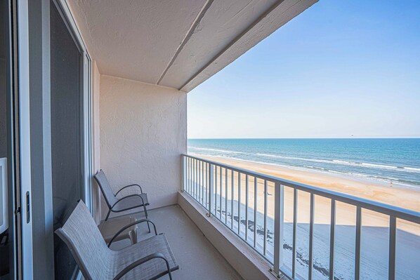 A balcony with a view of the beach, featuring a railing and two chairs. - Southpoint 506 in Ponce Inlet, FL (Ponce Inlet)